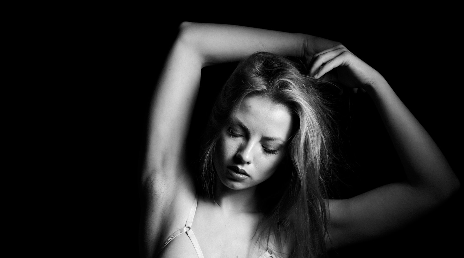 a woman in a bra is holding her hair